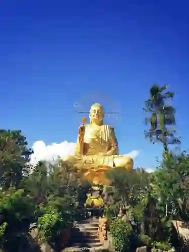 Estátua dourada de Buda ao ar livre entre árvores