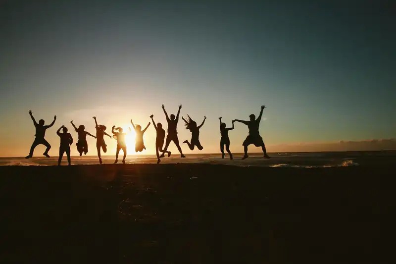 Silhuetas de pessoas saltando ao pôr do sol